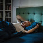 Anxious, mature man trying to sleep at night. Dealing with sleeping disorder. Tossing in messed bed sheets. Blurred motion
