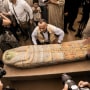 People surround Mostafa Waziri as displays a recently unearthed ancient wooden sarcophagus