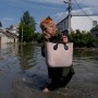 A local resident makes her way through a flooded road after the walls of the Kakhovka dam collapsed overnight, in Kherson, Ukraine