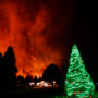 A Christmas tree is still lit as fires rage in the background in Louisville, Colo. on December 30, 2021.