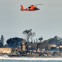 Image: A coastguard helicopter passing over damage caused by wildfires in Lahaina, Hawaii on Thursday, Aug. 10, 2023.