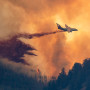 GUNNISON, COLORADO - JULY 26: A plane drops retardant as smoke billows and flames rise from the Lowline fire on July 26, 2023 near Gunnison, Colorado. The US Forest Service said the fire was started by lightning and has forced evacuations in the area.