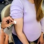 A pregnant young woman receives a vaccine at a preventive examination by a doctor