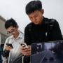 People look at newly launched smartphones at a Huawei flagship store after the company unveiled new products in Beijing