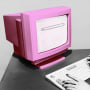 Pink vintage computer on a dark gray desk and gray background