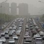 Vehicles travel on a road shrouded in smog during a sandstorm warning in Beijing on April 13, 2023. 