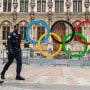 French police walk past Paris' City Hall where the five-Olympic rings are on display