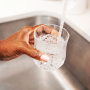 Woman pouring herself a glass of tap water from the kitchen sink