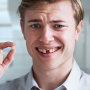 Man holding his missing tooth.