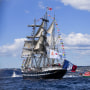 Belem, a three-masted sailing ship, adorned with flags from various countries, sails in the sea