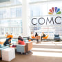 Comcast logo on glass wall in front of office workers. 