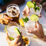Group of people celebrating toasting with cocktails - cropped detail with focus on hands