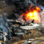 Debris from a Norfolk Southern freight train lies scattered and burning along the tracks