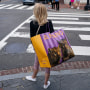 A woman carries a large shopping bag as she waits on a sidewalk