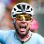 Mark Cavendish crosses the finish line and raises a fist in the air