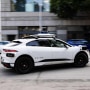 A white Waymo robotaxi vehicle driving on the street