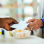 A man handing a prescription to a pharmacists