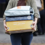 A USAID staff member carries a box and bag with personal belongings