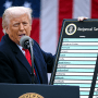 Donald Trump speaks into a microphone at a podium and holds a sign titled "reciprocal tariffs" with a list of countries and percentages