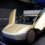 A Tesla Robotaxi vehicle, painted gold, inside of a showroom