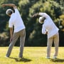 Rear view of senior couple stretching in park