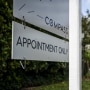 A Compass sign that reads "Compass, Appointment Only" outside of a white house