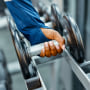 Athlete picking up dumbbell in a gym.