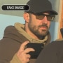 A deepfake image showing a man resembling Alex Pretti holding a cell phone in his hand while standing near a law enforcement officer, who wears a flak jacket.