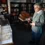 A woman stands in front of an architectural model encased in glass.