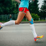 Image: A girl athlete running with her knees in blue kinesiology taping 