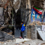 A boy peers into a damaged residential building.