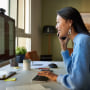 Businesswoman talking on smart phone at desk
