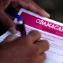 Image: A man fills out an information card during an Affordable Care Act outreach event