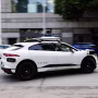 A white Waymo robotaxi vehicle driving on the street
