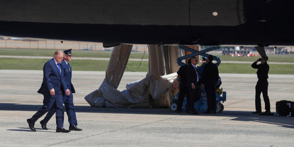 Air Force personnel inspect the inflatable slide on Trump’s Qatari gift jet, bravely testing whether U.S. national security can also be deployed with a single oops button.