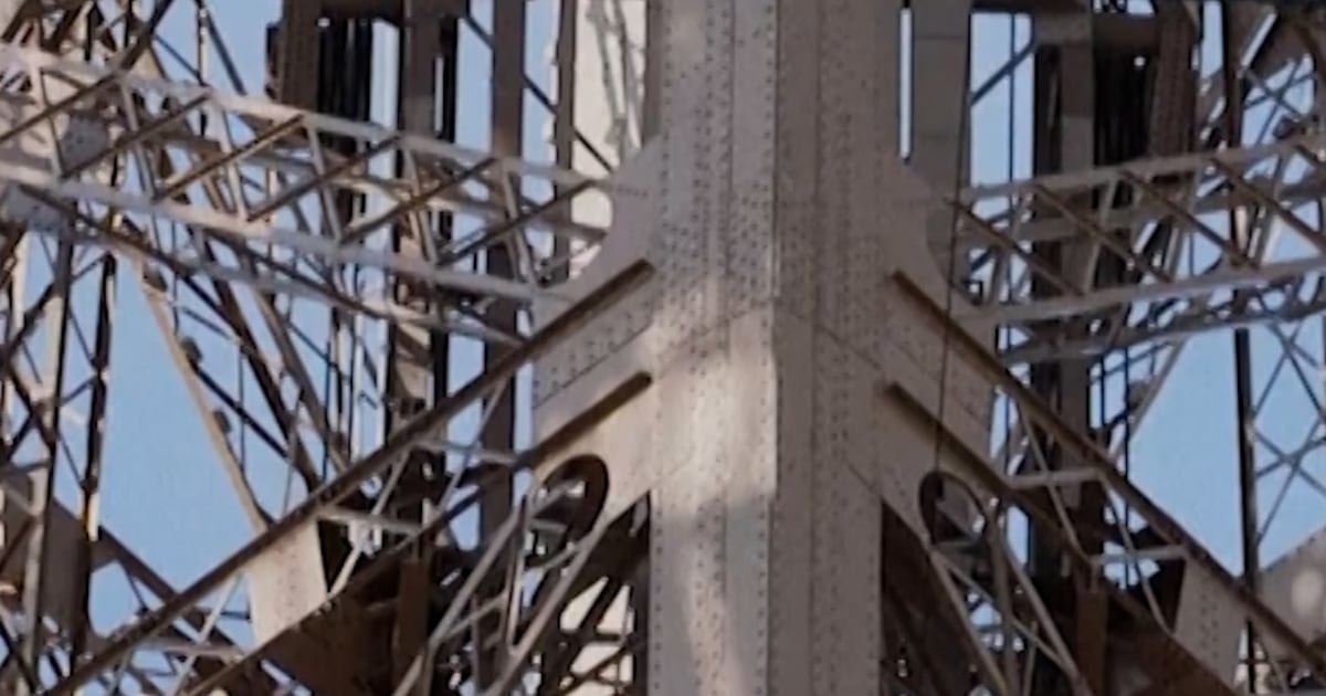 Tourists walk hanging Eiffel Tower bridge