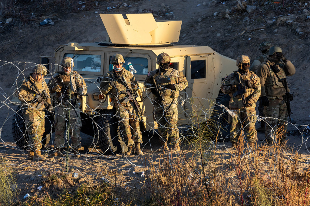 Three migrants who had managed to evade National Guard and cross the Rio  Grande onto U.S. territory wait for Border Patrol along a wall set back  from the geographical border, in El